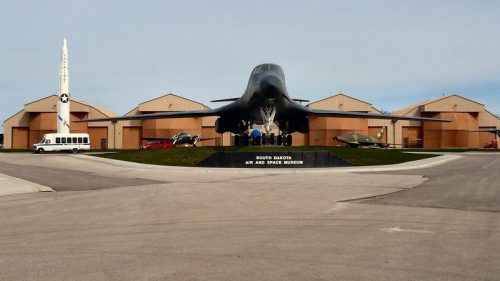 Exterior view of the South Dakota Air and Space Museum, featuring aircraft and a missile in front of hangars.