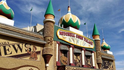 Colorful facade of Mitchell Corn Palace, featuring unique architecture and decorative murals, under a blue sky.