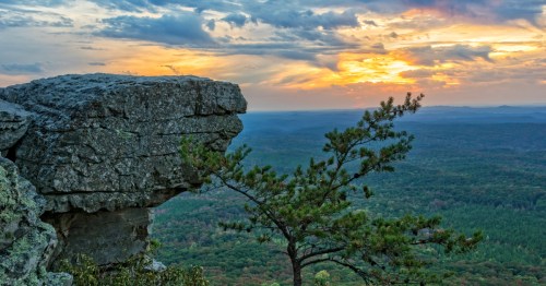 Overlook with grey rocks, green trees, and clouds at sunset in Alabama
