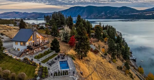 An aerial view of a waterfront cabin near Lake Chelan, Washington, with a large yard and pool on an autumn day.