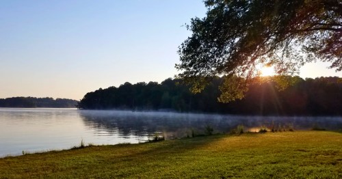 The sun shines over the trees and onto Lake Hartwell at Tugaloo State Park in Georgia.