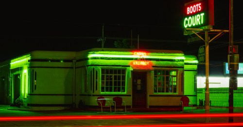 A nighttime look at the Boots Court Hotel in Carthage, Missouri, illuminated in neon lights.