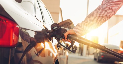 Man handle pumping gasoline fuel nozzle to refuel at petrol station. Summer travel survey on rising gas prices.