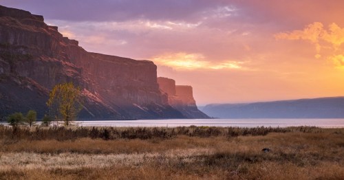 A pink-hued sunset lights up the sky above Banks Lake and Steamboat Rocks State Park in Washington.