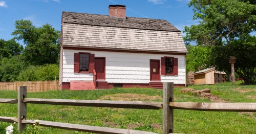 A historic red-and-white house behind a wooden fence in Titusville, New Jersey