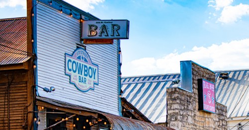 Historic storefronts in Bandera, Texas, display Western charm with metal roofs, glowing string lights, and signs for local bars and entertainment venues in the heart of the Cowboy Capital of the World.