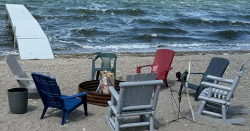 Beach seating and fire pit area next to a private dock at a lakefront Airbnb in Warwick, ND.