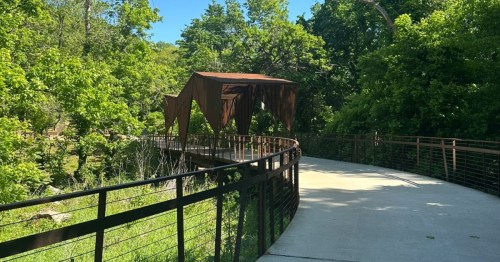 A paved bike trail leads toward a covered bridge in Bentonville, Arkansas.