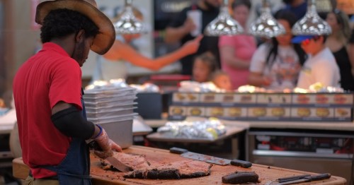 A Bucc-ees chef slicing up brisket for sandwiches as a crowd looks on.