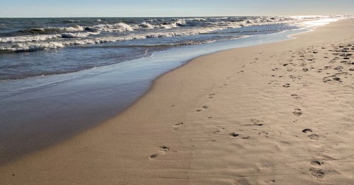 Footprints in the sand along the water of Lake Michigan at Gillson Beach in Wilmette, Illinois