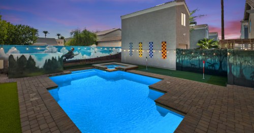 Backyard pool at a themed Airbnb in Arizona featuring wizard-inspired murals, house banners, string lights, and a spa.