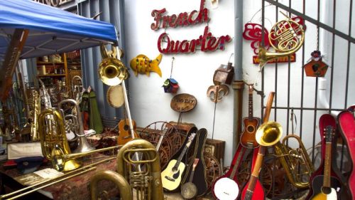 A vibrant display of musical instruments and decor in a French Quarter setting, featuring brass, string, and wooden items.