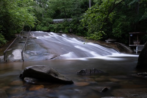 A white waterfall gushes onto sitting rocks surrounded by trees at Sliding Rock in North Carolina.