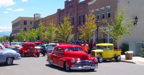Several vintage cars on Main Street in Minden, Nevada, featuring brick storefronts.