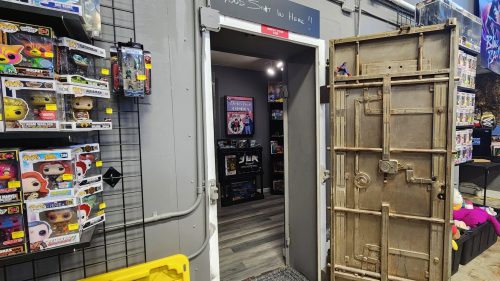 A doorway with a large metal door propped open, leading into a colorful room filled with collectibles and decorations.