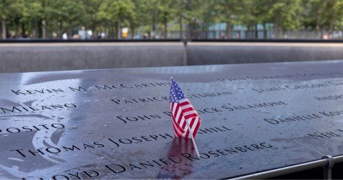 An American flag rests on a victim's name plate at one of the the twin waterfall pools at the National September 11 Memorial and Museum.