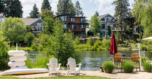 Two white chairs on the sandy shoreline in Bend, Oregon on the river.