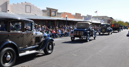 Vintage automobiles cruise through downtown during the Gold Rush Days parade in Wickenburg, Arizona, as crowds watch from the sidewalks.
