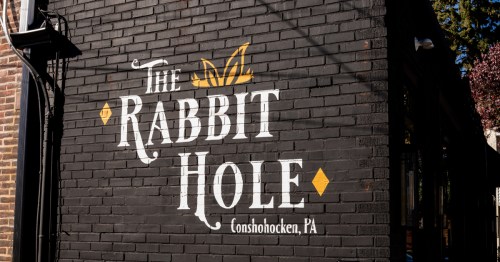The brick exterior wall of The Rabbit Hole restaurant in Conshohocken, PA with it's name and logo.