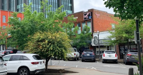 Downtown Fayetteville, Arkansas, with cars lined up and shops in the back.