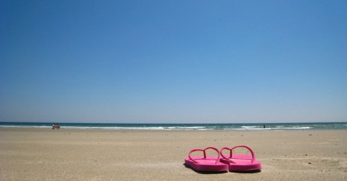 A pair of pink flip flops sit on the sands of Ogunquit, Maine's Footbridge Beach.