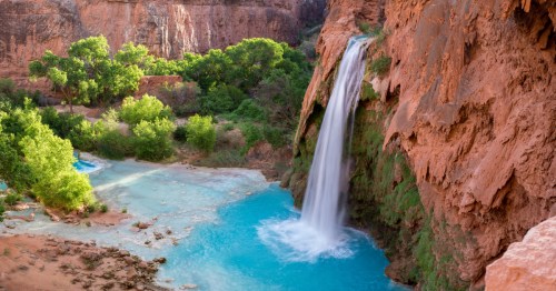 Havasu Falls cascades into a turquoise pool between towering red canyon walls in the Havasupai Reservation, Arizona.