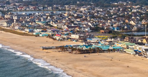 An overhead view of the Point Pleasant Beach boardwalk in New Jersey, with amusement parks and housing visible next to the beach.