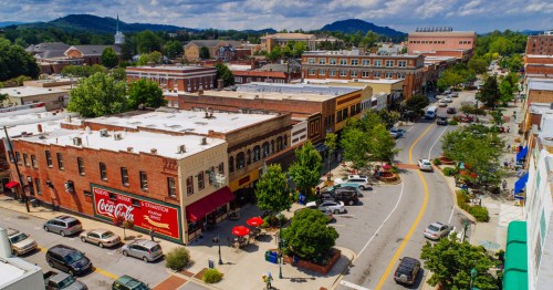 An aerial view of the charming town of Hendersonville, NC, complete with brick buildings, trees, and cars parked.