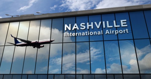 an airplane in flight reflected in the windows of a terminal at Nashville International Airport (BNA) in Tennessee