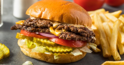 a double smash burger with cheesem red onion, tomato and pickles with a side of fries