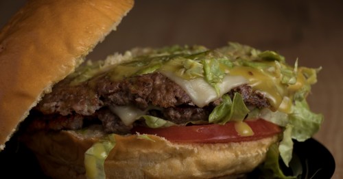 closeup of a smashburger with cheese, lettuce and tomato