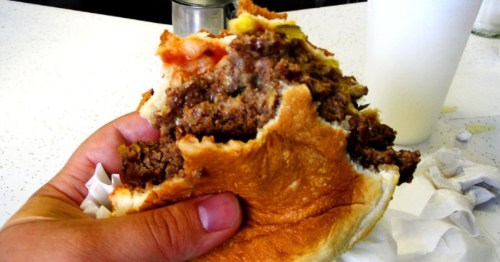 a hand holds a half-eaten burger at clyde's in sault ste. marie, michigan