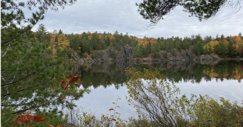 Calm, glassy water reflecting colorful fall trees and cliffs at Echo Lake, Michigan.