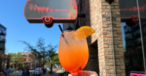 A hand holding a spritz cocktail outside of Happy Camper in Chicago, Illinois.
