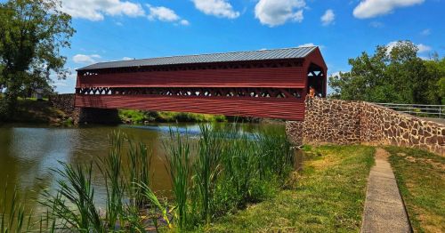 Views of the red Sachs Covered Bridge in Pennsylvania, spanning over a creek, surrounded by greenery.