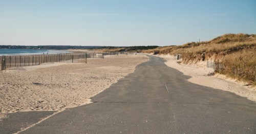 A long concrete road stretches out alongside Horseneck Beach in Massachusetts on the left on a clear day.