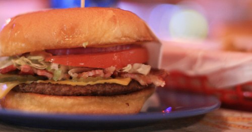 A cheeseburger on a platter with all the toppings.