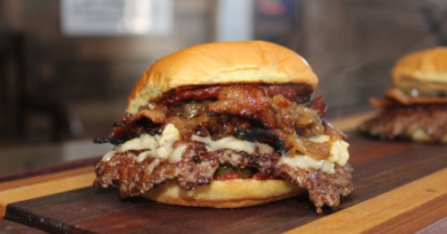 view of a smash burger topped with bacon, cheese, and more at Leo’s Smash Burgers and Dogs in maryland