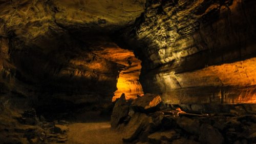 A dimly lit cave interior with rocky formations and an illuminated column, creating a mysterious atmosphere.