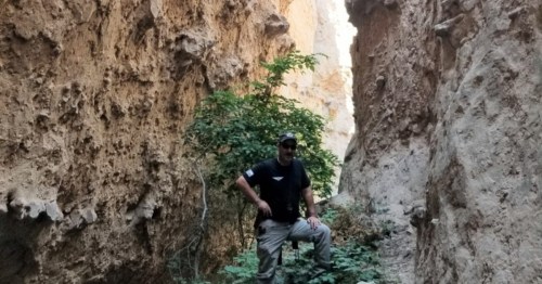 Hiker standing inside a narrow rock crevice at Devil's Den, Nebraska.