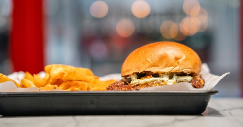 a smashburger and fries served on a silver food tray